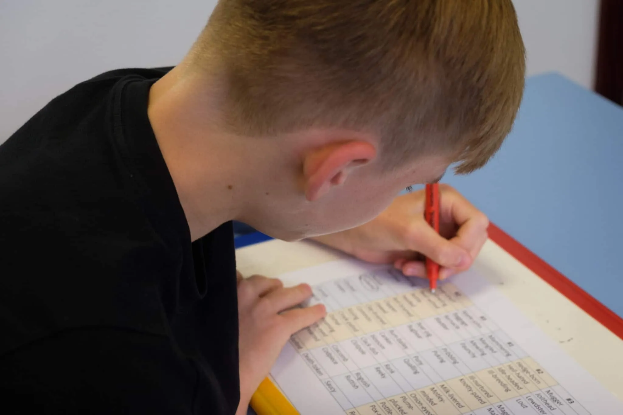 A pupil working through a spelling sheet with a red pen at the Top Grades centre
