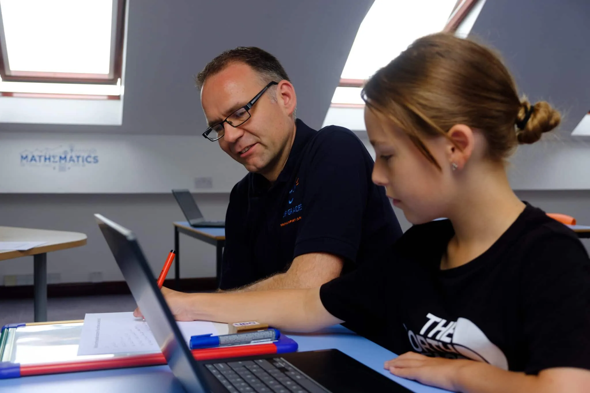 Richard, the founder, helping a pupil with a Maths problem at a laptop in a Top Grades classroom
